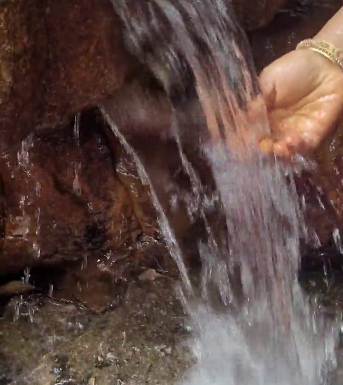 特写镜头：手和腿接触溪水。