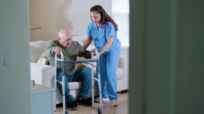 西班牙裔家庭护理人员帮助老年男性使用助行器。