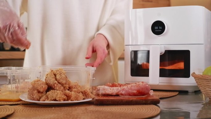 女人为空气炸锅准备鸡肉条