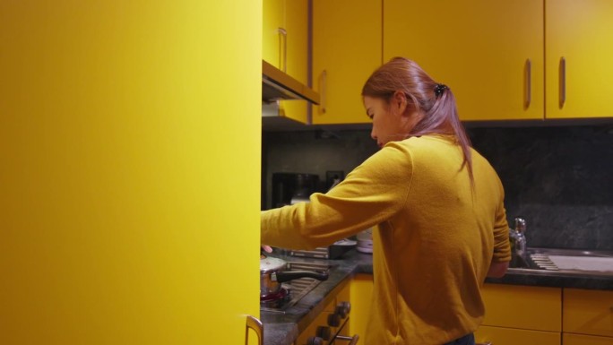 女人在公寓的黄色厨房里准备食物。