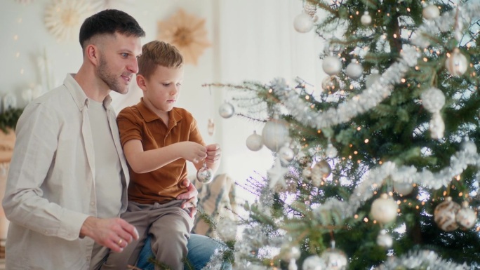 爸爸和孩子在圣诞树上挂装饰球。