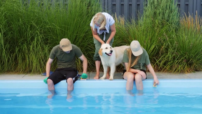 一个紧密团结的家庭在后院清理游泳池的边缘，旁边有他们的金毛猎犬。