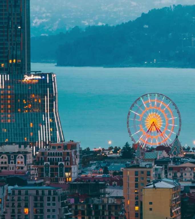 巴图米，阿贾拉，格鲁吉亚。高处视角的摩天轮位于奇迹公园的海滨长廊，游乐城市公园在傍晚时分。傍晚转为夜