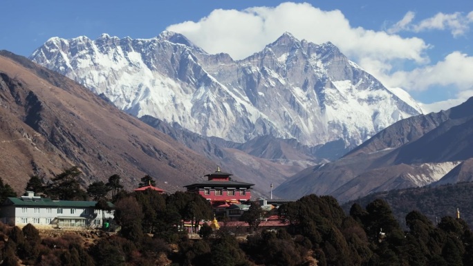 尼泊尔山区偏远村庄的航拍视角，展示了传统的建筑风格和背景中雄伟的雪山之巅