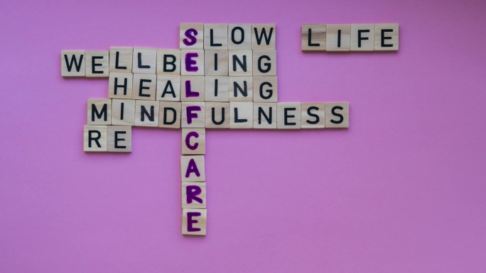 时间推移：粉色背景上“自我关怀”字样的俯视图。极简主义创意填字游戏概念。传达慢生活、身心健康、疗愈、