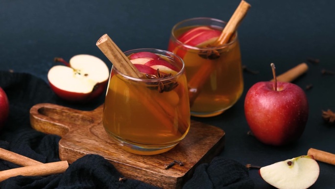 杯中温暖的苹果酒，配有肉桂棒和八角，佐以新鲜苹果。