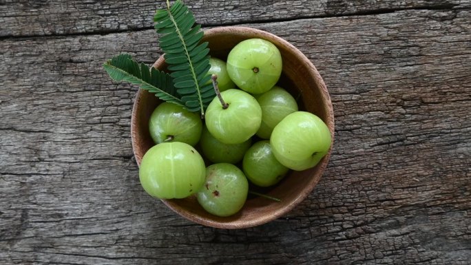 新鲜的印度醋栗（余甘子，Phyllanthus emblica）带叶的水果，置于木质背景上。