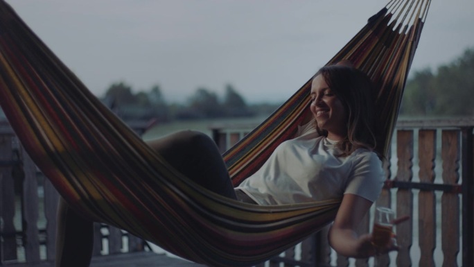 女人躺在吊床上喝香槟。