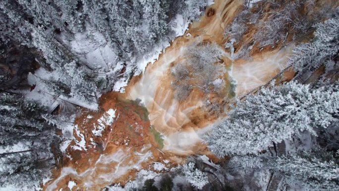 无人机视角，航拍中国四川松潘牟尼沟扎嘎瀑布。冬季晴天，壮观的瀑布与雪松林。4K实时镜头，旅行概念。