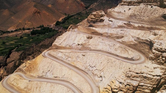 一条蜿蜒的山路穿过尼泊尔干燥的地形，山谷中可见绿色的梯田。