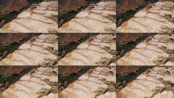 一条蜿蜒的山路穿过尼泊尔干燥的地形，山谷中可见绿色的梯田。