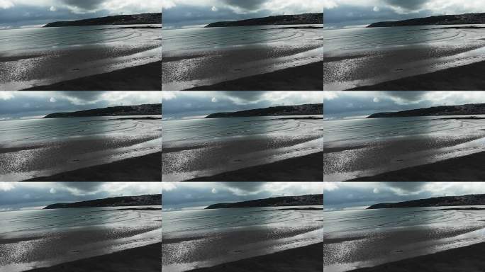 阴天下的宁静海岸线，平静无人的沙滩，轻柔的海浪