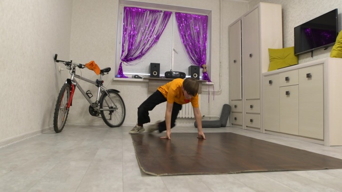 一个少年在他装饰着自行车的房间里学习霹雳舞。