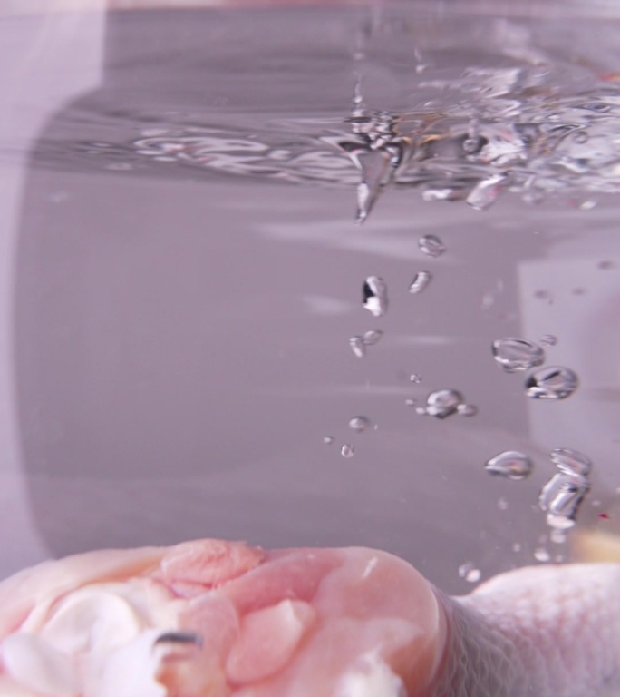 新鲜生鸡腿投入冰水冒泡水花特写慢动作素材