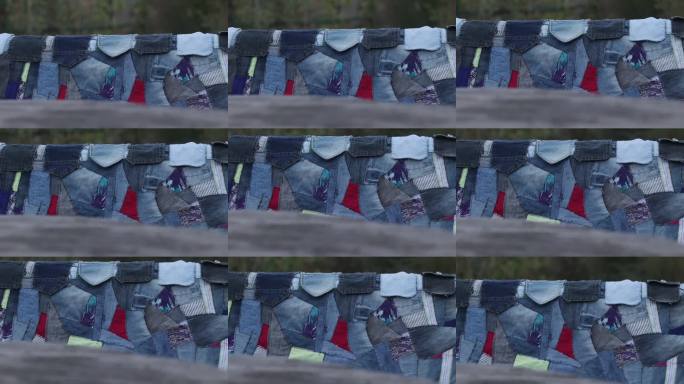 手工拼接风格的格子牛仔布料放在花园里用托盘制作的木凳上。