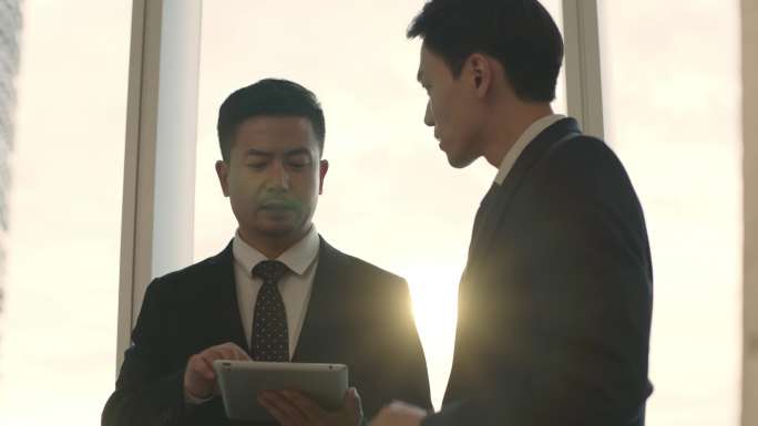 两名亚裔商务人士使用平板电脑交流讨论