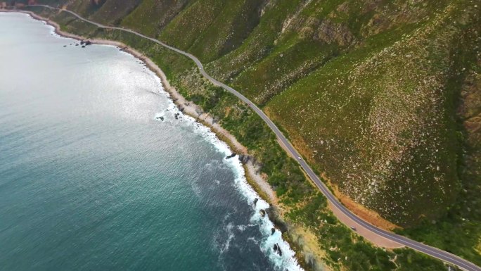 航拍车辆行驶在海湾旁美丽的峭壁海岸公路上