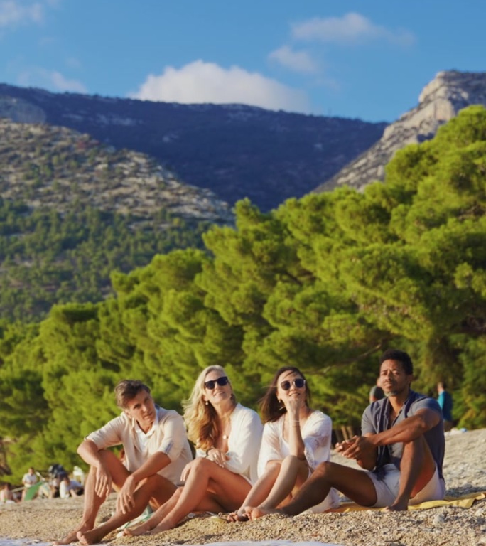 多样的朋友们在扎尔特尼拉特卵石海滩上享受生动的时刻，背景是充满活力的橙色天空。