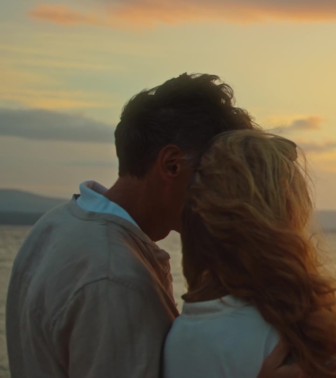 浪漫的成熟情侣在海滩上享受日落，一起微笑着看他们智能手机上的照片。