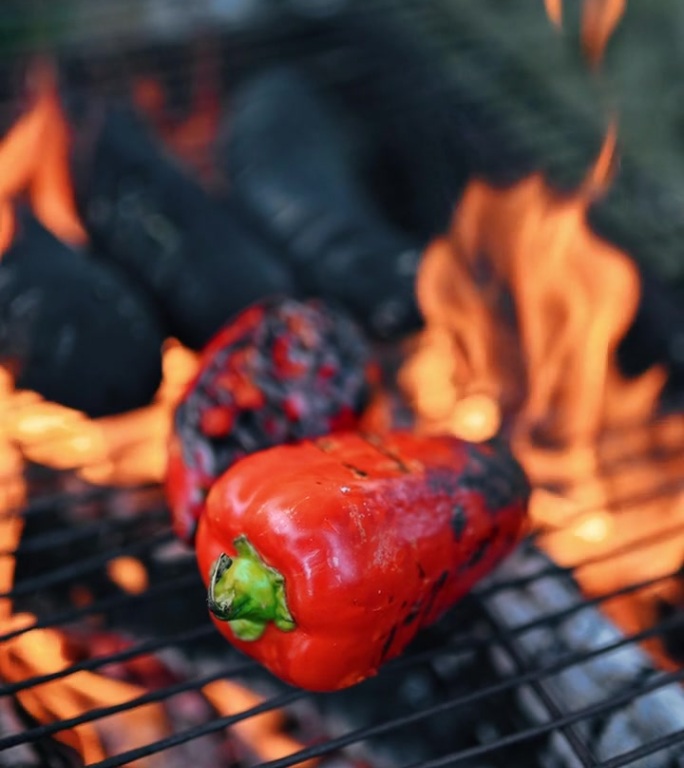在户外烹饪中，鲜红辣椒和番茄在明火上热烤的慢动作视频。