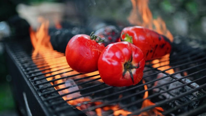 在户外烹饪中，鲜红辣椒和番茄在明火上热烤的慢动作视频。