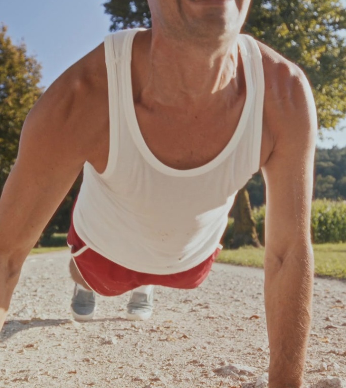有趣的中年白人男性复古运动员在户外充满活力地做俯卧撑。
