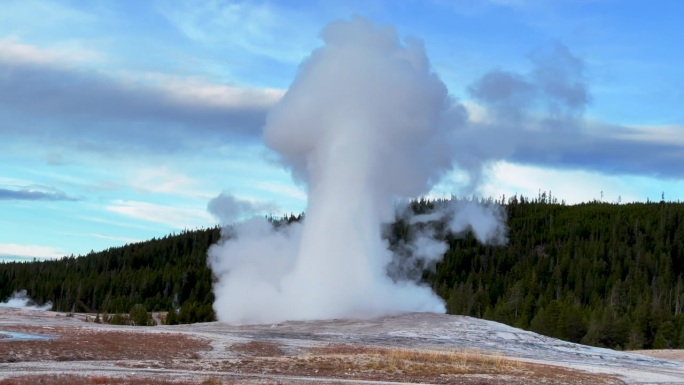 电影感的老忠实间歇泉日出日落喷发爆炸蒸汽黄石国家公园观景台上间歇泉盆地秋天美丽的蓝天慢动作平移跟随。