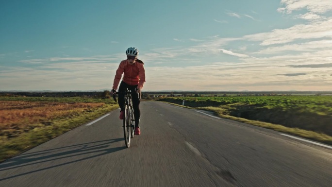 年轻的白人女性在乡村公路上享受风景优美的自行车骑行