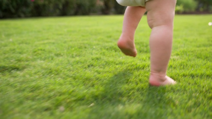 幼儿在花园草地上赤脚散步，享受户外时光