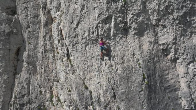 航拍：女性在自然攀岩区攀爬一条陡峭且具有挑战性的路线。