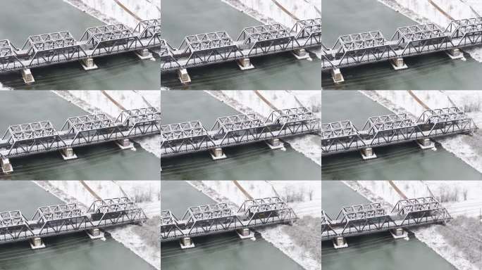 无人机拍摄的锈带区钢制铁路桥，火车正驶过冰冷的河水