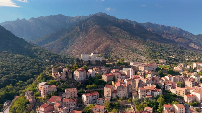贝尔维代尔中世纪城堡的航拍视角，周围是充满活力的景观和远处的山峰。科西嘉，科尔泰，法国