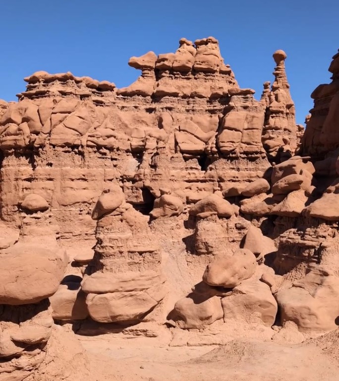 风景镜头平移，展示了犹他州哥布林谷州立公园中，哥布林般的砂岩石柱和独特的岩石构造，背景为晴朗的蓝天。