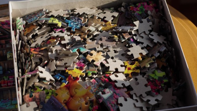 拼图块在晨光中的盒子里。手持慢动作拍摄。