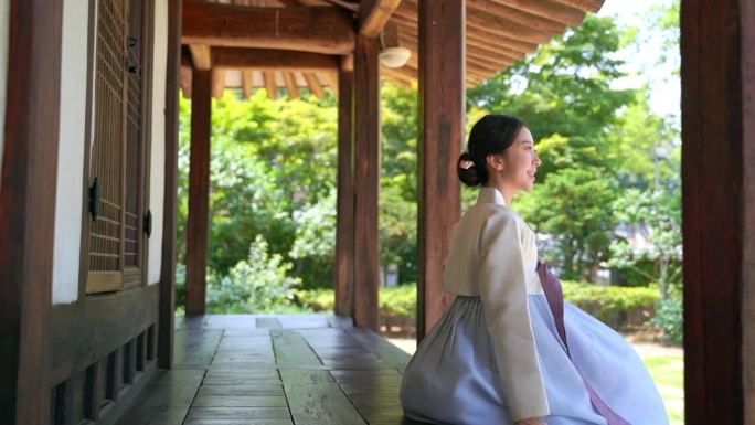身穿韩服（朝鲜王朝的传统韩国服饰）的女性坐在大青马鲁（韩国传统木地板走廊）上。