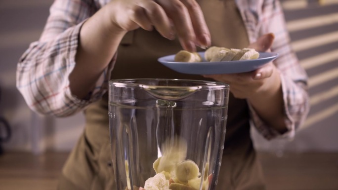 女士准备制作冰沙，扔进香蕉块