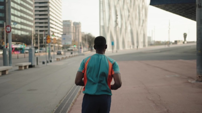 非洲裔美国男子在城市晨跑的背影。