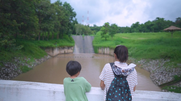 亚洲母亲和儿子观看大坝景观 - 宁静的自然时刻