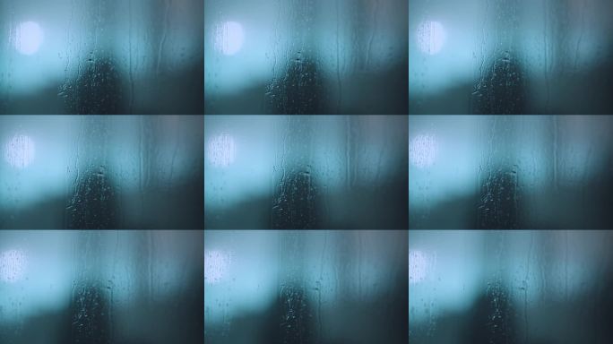 雨滴在玻璃窗上流淌，映衬着青色的灯光。