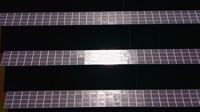 太阳能电池板在平坦表面上排成平行线，在正午时分，太阳能农场反射着阳光。