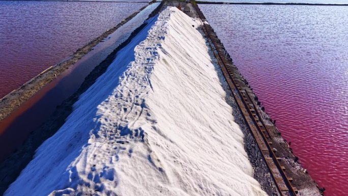 雄伟的盐山在日落时分，在迷人的盐沼环境中，在闪闪发光的水池之间升起。