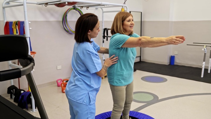 老年女性在迷你蹦床上做深蹲。